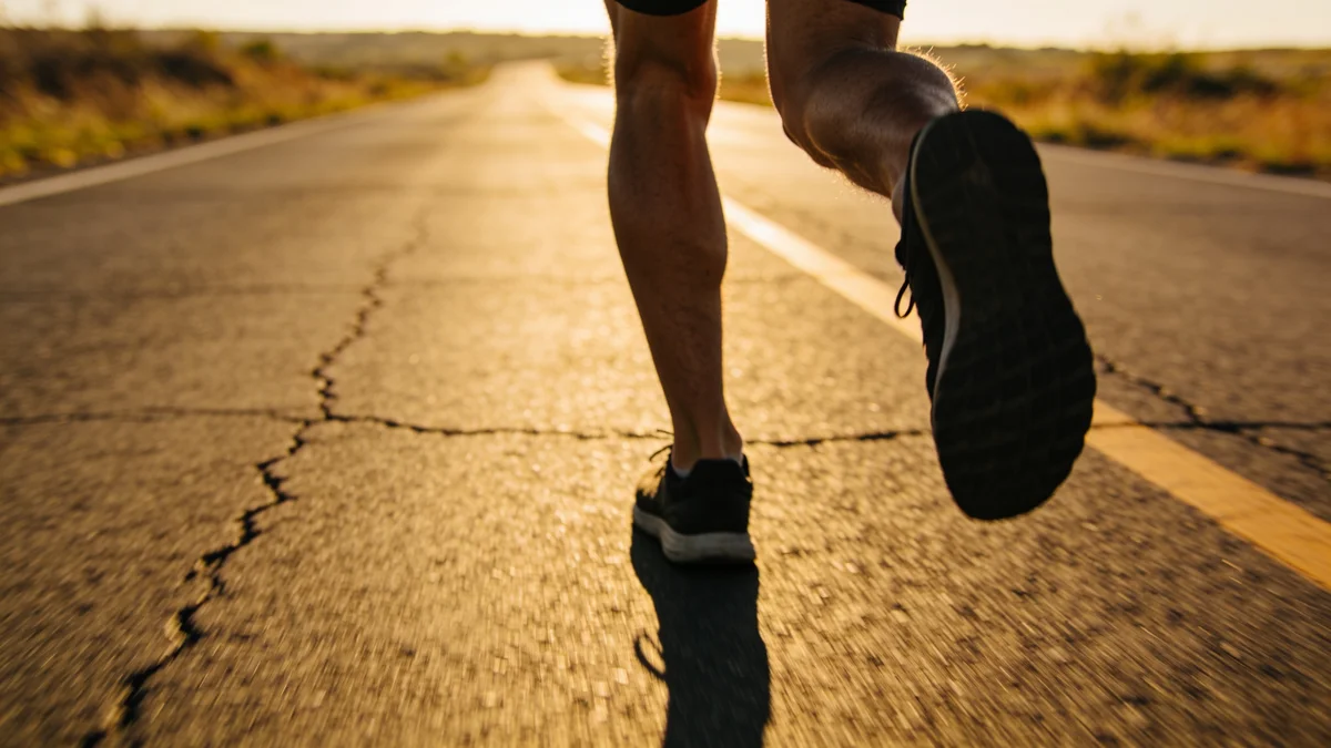 Las mejores zapatillas de running de 2026 Corredor entrenando con zapatillas de running en carretera al atardecer