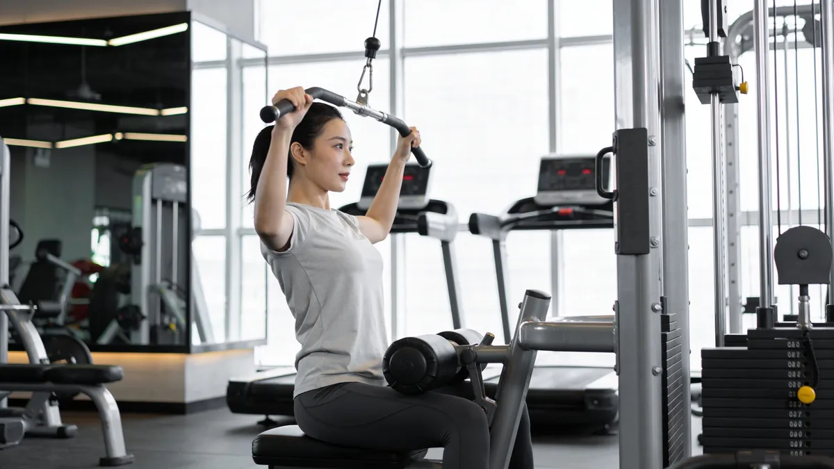 Rutina Push Pull Legs (PPL): la guía completa para organizar tu semana Mujer haciendo jalón al pecho en polea durante el día de tirón de una rutina push pull legs